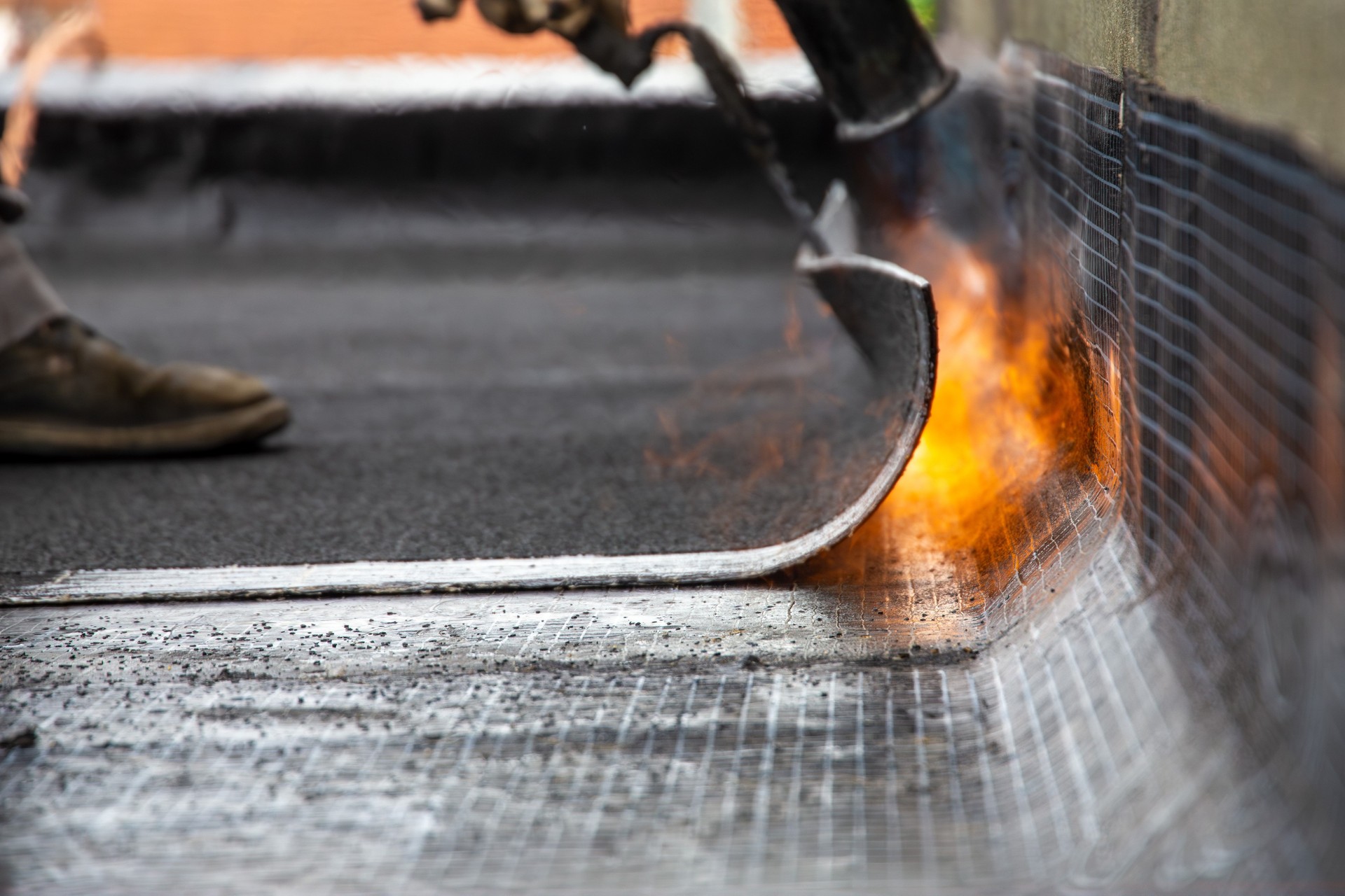 Roofer during waterproofing work with bitumen membranes